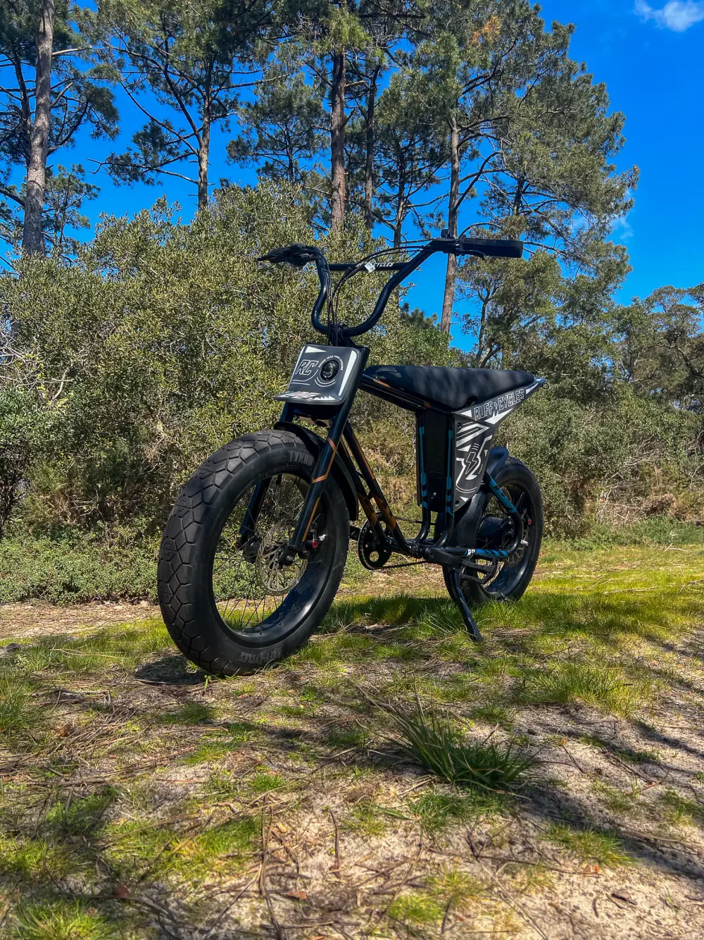 Vélo électrique Ruff Cycles Lil Loco noir de profil dans la forêt de pins landaise